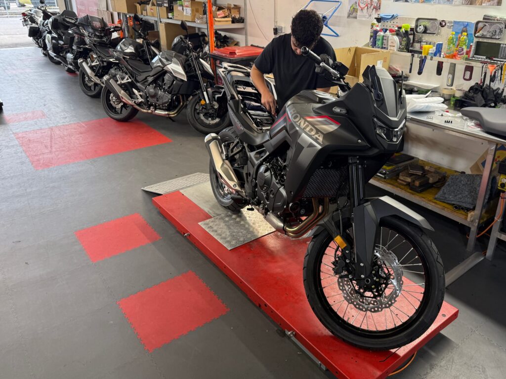 Mechaniker arbeitet in der Werkstatt an einem Motorrad auf der Hebebühne